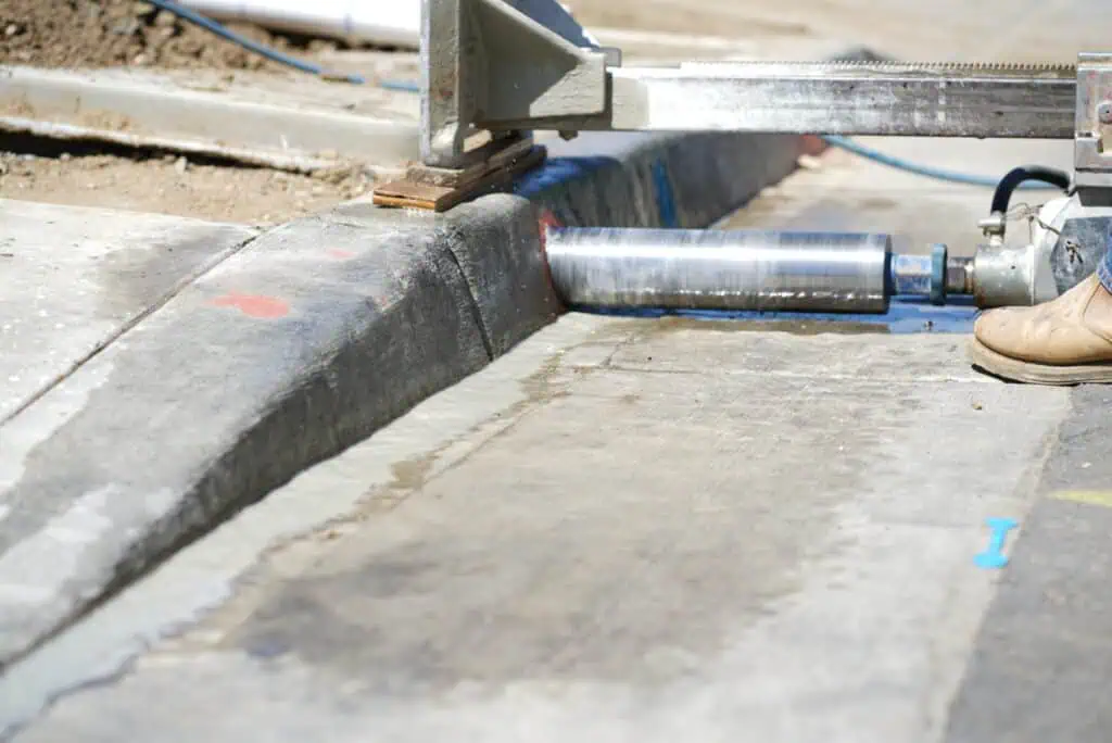 Curb core drilling process using professional equipment for accurate concrete cutting.
